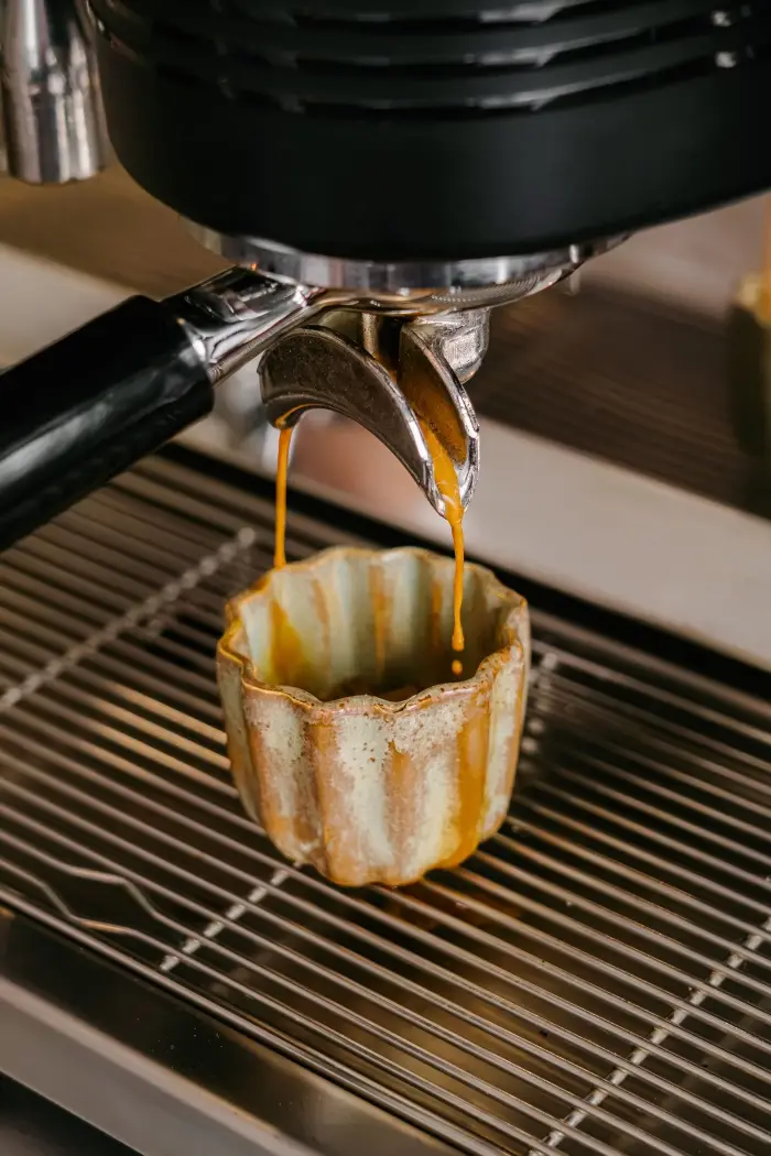 Espresso de café de spécialité coulant dans une tasse artisanale en forme de cannelé chez Coco Cannelés à Paris