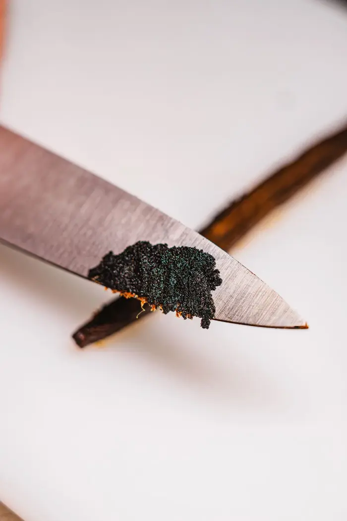 Grains d'une gousse de vanille bourbon grattés au couteau, l'ingrédient signature des cannelés vanillés de Coco Cannelés
